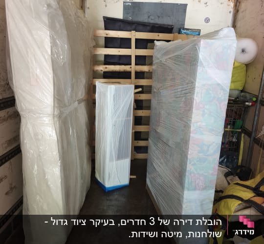 רהיטים ומזרונים עטופים בניילון נצמד מסודרים בתוך משאית הובלה